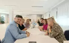 zdjecie przedstawiające osoby siedzące na krzesłach przy stole i rozmawiające