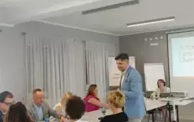 zdjecie przedstawiające osoby siedzące na krzesłach przy stole i rozmawiające